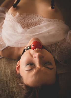 Нимфоманка с кляпом во рту дрочит письку